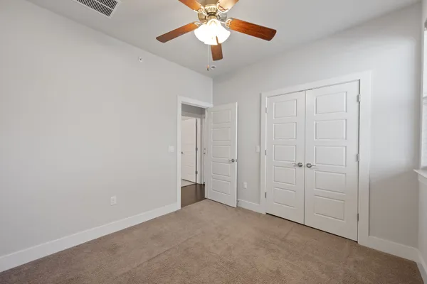 a view of an empty room and chandelier fan
