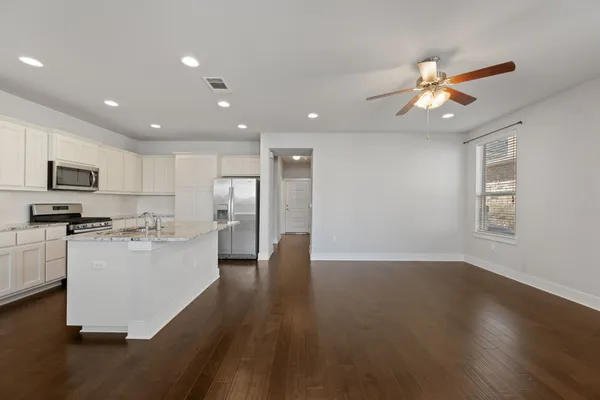 a kitchen with stainless steel appliances granite countertop a refrigerator a stove a sink dishwasher and a oven with wooden floor