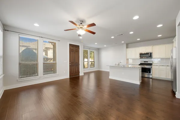 a view of an empty room with kitchen view and a window
