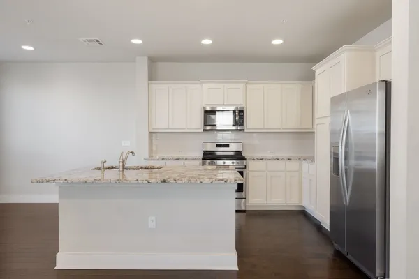 a kitchen with stainless steel appliances granite countertop a refrigerator a sink a stove and white cabinets