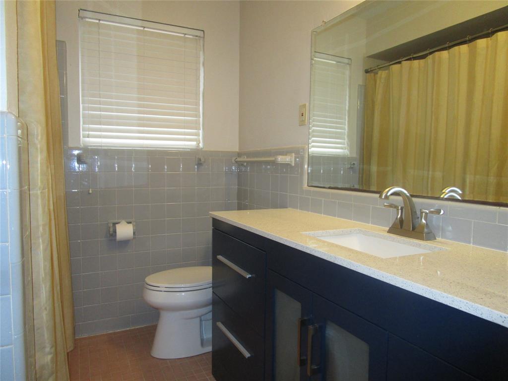7128 Clemson Drive Dallas, TX 75214 - Photo 9 of 10 a bathroom with a sink a toilet and mirror