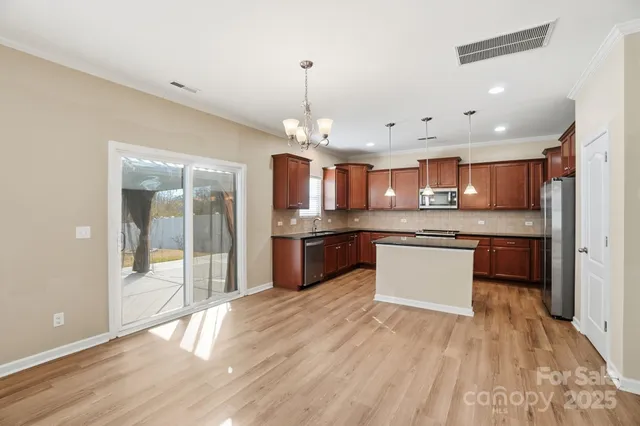 a large kitchen with granite countertop a large counter top a sink stainless steel appliances and cabinets