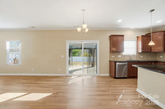 a view of a kitchen with a sink and dishwasher a stove top oven with wooden floor
