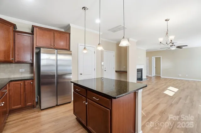 a kitchen with stainless steel appliances granite countertop a refrigerator a oven and a wooden floors
