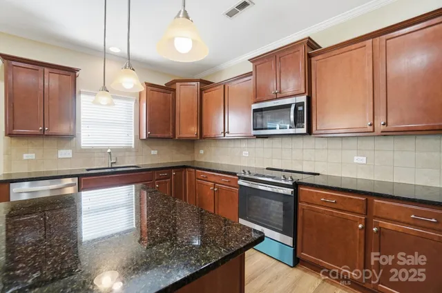 a kitchen with stainless steel appliances granite countertop wooden cabinets a stove a sink and dishwasher
