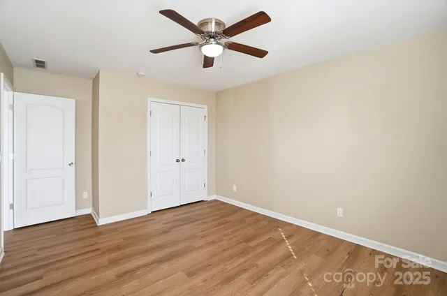an empty room with wooden floor and a ceiling fan