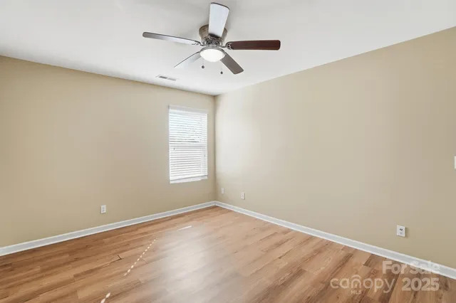 an empty room with a window and a fan