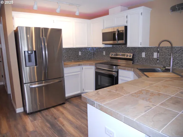 a kitchen with stainless steel appliances a refrigerator sink and microwave