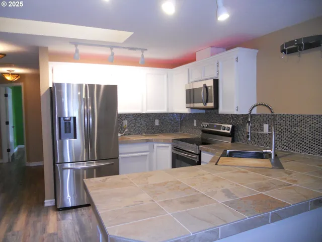 a kitchen with stainless steel appliances a refrigerator sink and microwave