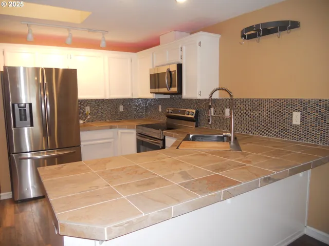 a room with stainless steel appliances lots of counter top space and furniture