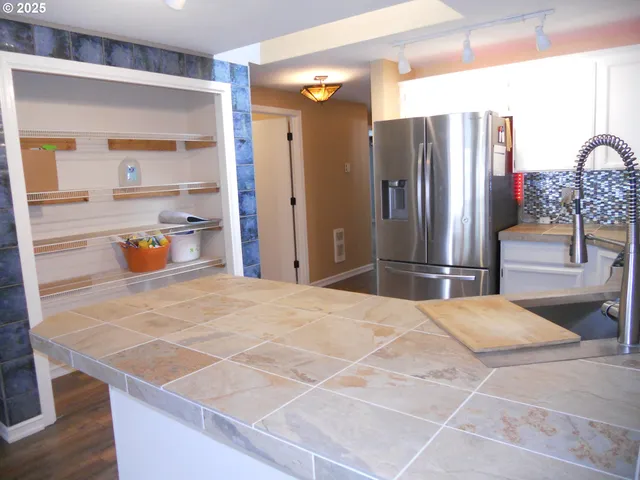 a kitchen with stainless steel appliances kitchen island granite countertop a refrigerator and a sink