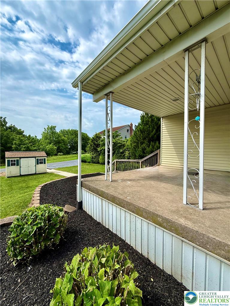 5540 Main Street Whitehall, PA 18052 - Photo 5 of 53 A quaint front porch provides a welcoming entrance, complemented by a neatly manicured landscape with a detached storage shed.