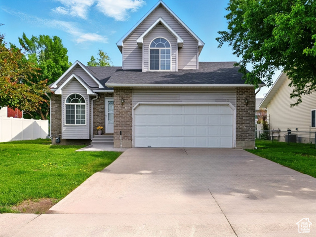 495 West 1330th Street North Logan, UT 84341 - Photo 1 of 1 View of front facade with brick siding, driveway, an attached garage, and a shingled roof