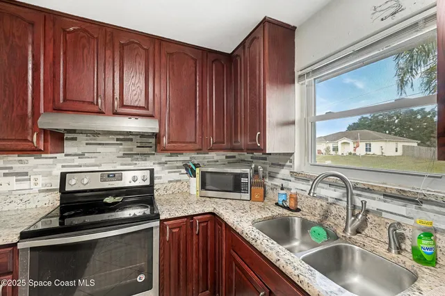 a kitchen with granite countertop a sink stove and cabinets