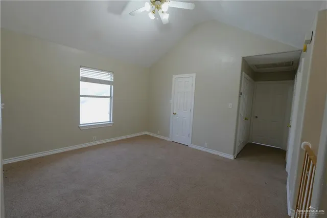 an empty room with a chandelier fan and windows