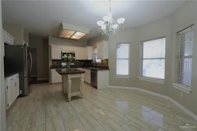 a kitchen with stainless steel appliances a stove top oven a sink dishwasher a refrigerator and a dining table with wooden floor