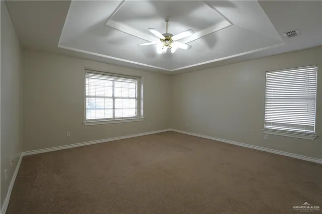 an empty room with a chandelier fan and windows