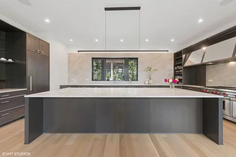 a living room with kitchen island granite countertop a sink and a wooden floor