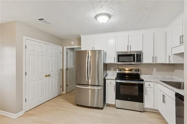 a kitchen with stainless steel appliances a refrigerator stove and white cabinets