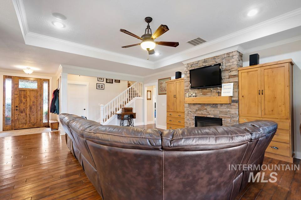 8271 Washoe Road Fruitland, ID 83619 - Photo 15 of 29 Living area featuring wood-finish flooring, a stone-clad fireplace with a hearth, and built-in wood cabinetry