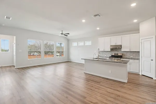a kitchen with stainless steel appliances granite countertop a stove a sink and a refrigerator with wooden floors