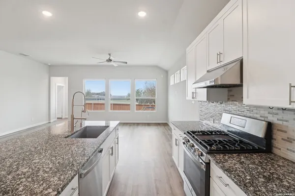 a kitchen with stainless steel appliances granite countertop a sink stove and cabinets