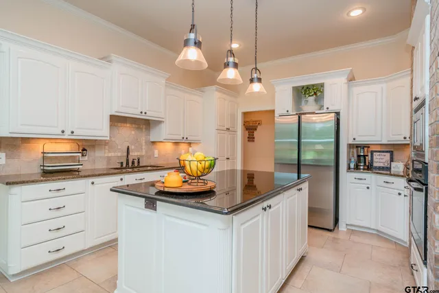 a kitchen with a stove a sink a counter top space and living room view