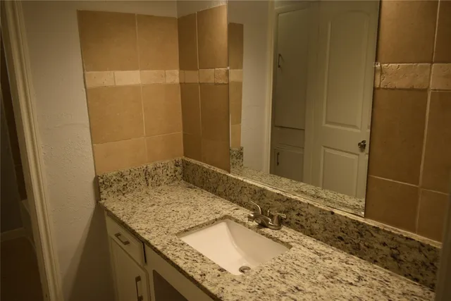 a bathroom with a granite countertop sink and a mirror
