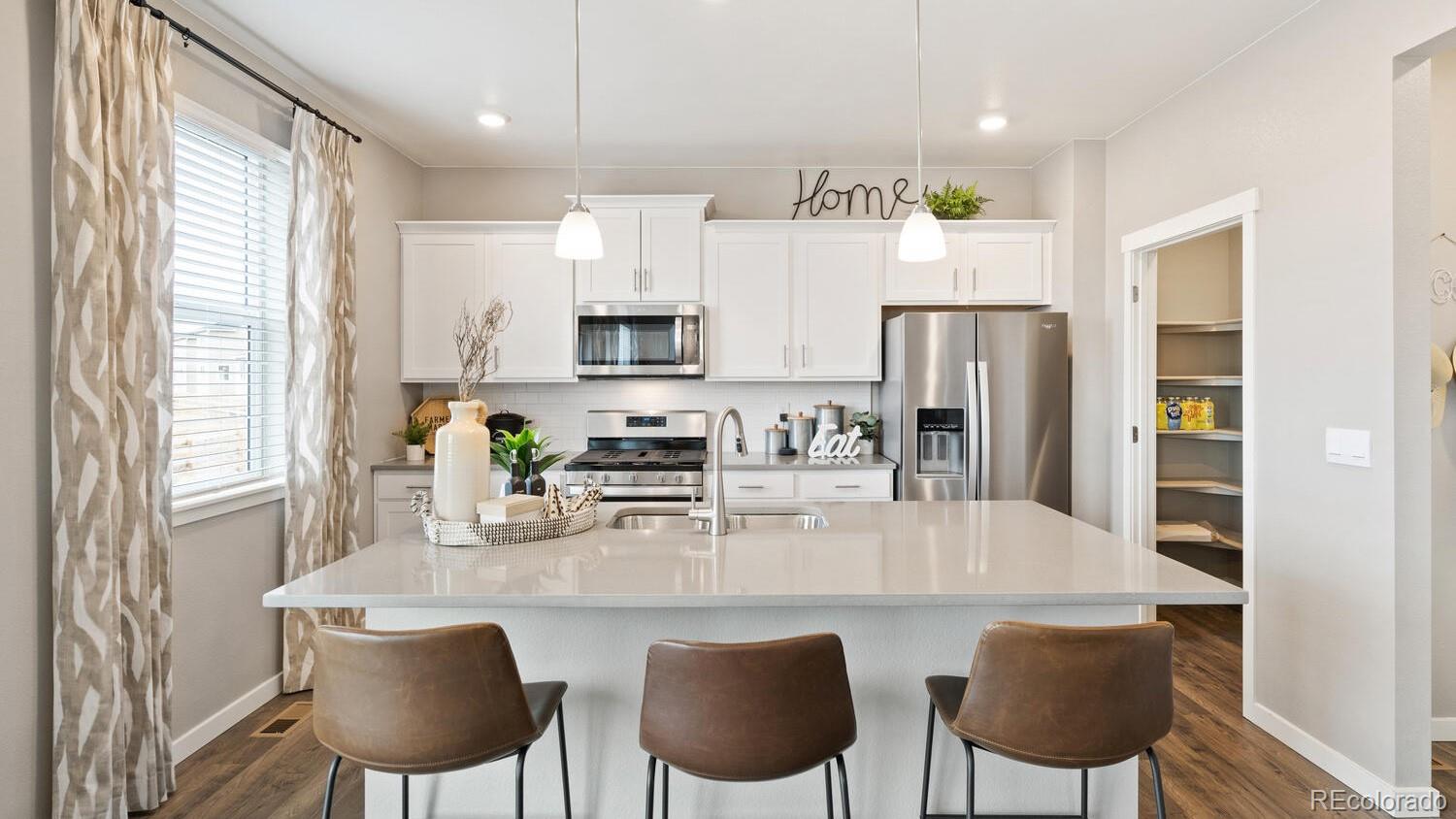 1531 Pinnacle Avenue Lochbuie, CO 80603 - Photo 11 of 25 a kitchen with stainless steel appliances a dining table chairs refrigerator and sink