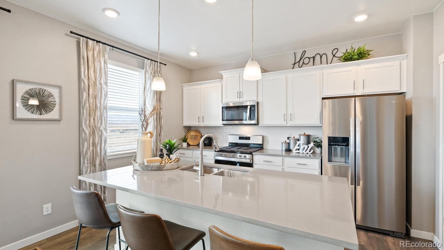 1531 Pinnacle Avenue Lochbuie, CO 80603 - Photo 10 of 25 a kitchen with stainless steel appliances a refrigerator a sink a stove a dining table and chairs
