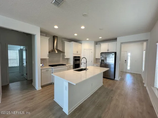 a large kitchen with stainless steel appliances a refrigerator and a stove top oven