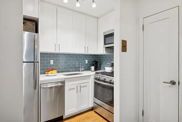 a kitchen with stainless steel appliances a refrigerator sink and white cabinets