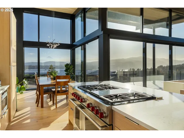 a kitchen with a stove a sink and a dining table with wooden floor