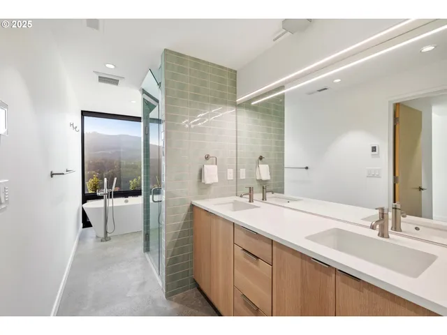 a bathroom with a sink double vanity granite tub shower and a mirror