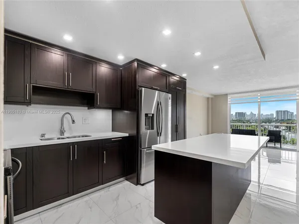 a kitchen with stainless steel appliances a sink dishwasher a refrigerator and a stove with wooden floor