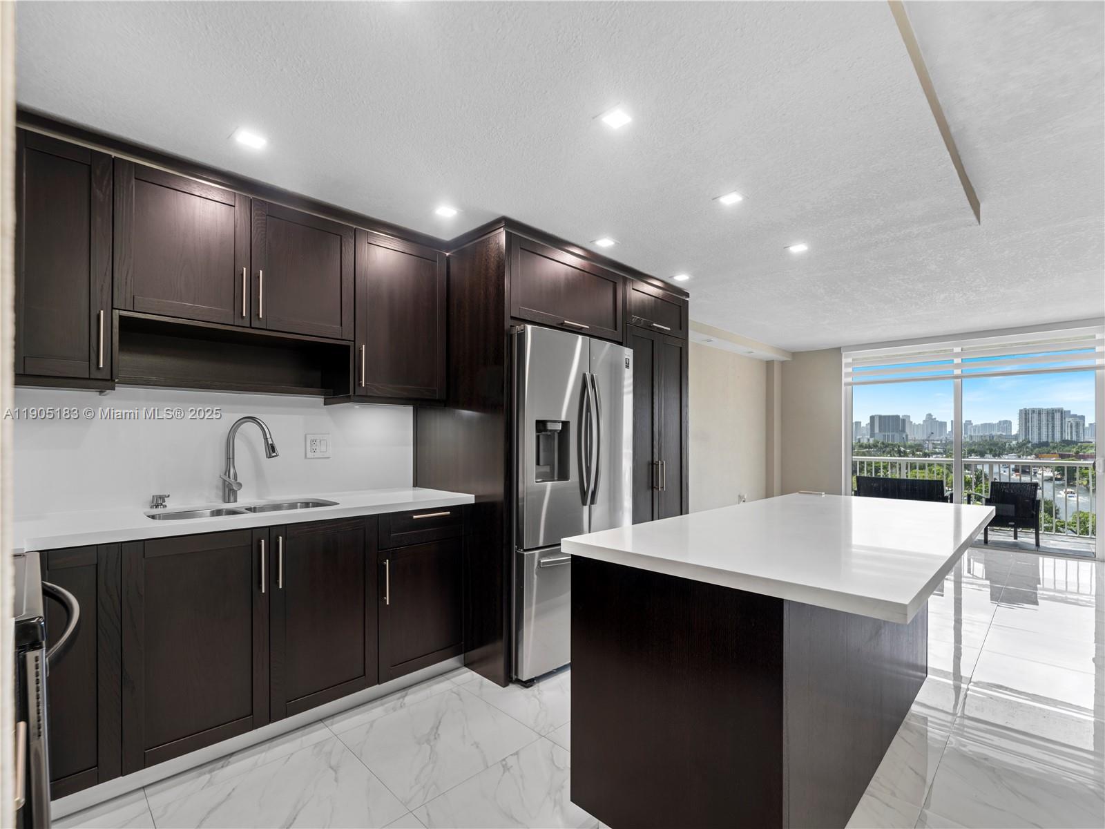 a kitchen with stainless steel appliances a sink dishwasher a refrigerator and a stove with wooden floor