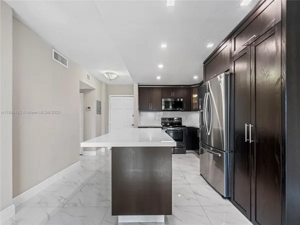 a large kitchen with a large counter top stainless steel appliances and cabinets