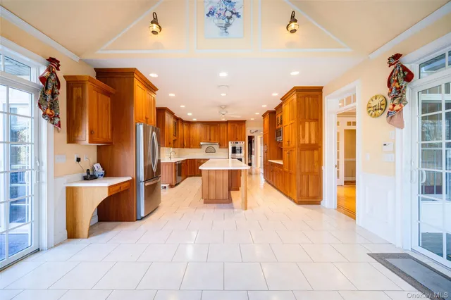 a large white kitchen with stainless steel appliances kitchen island granite countertop a refrigerator and a sink