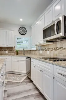 a kitchen with granite countertop white cabinets white stainless steel appliances and a sink