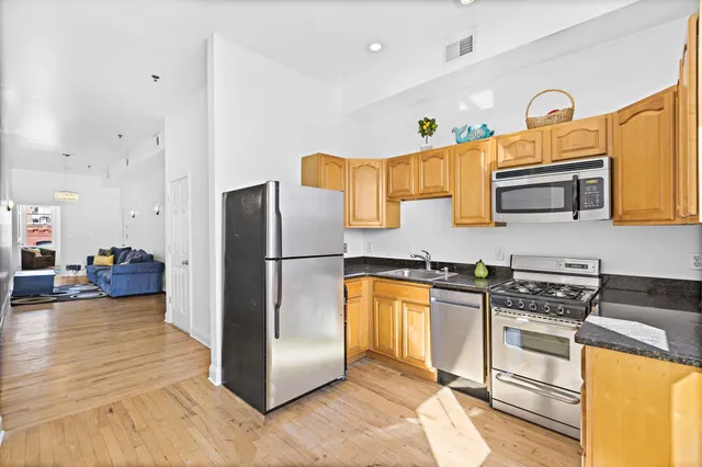 a kitchen with stainless steel appliances a refrigerator a stove a sink a oven and dining table with wooden floor