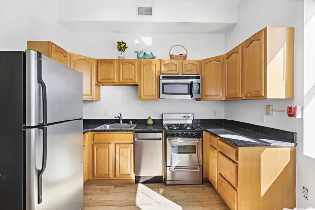 a kitchen with stainless steel appliances granite countertop a refrigerator a stove and a sink