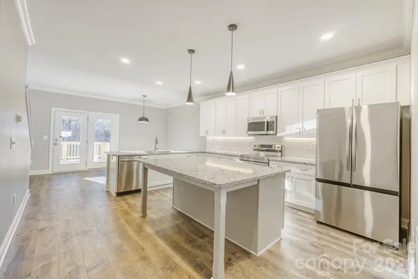 a kitchen with kitchen island a sink a stove a refrigerator and white cabinets