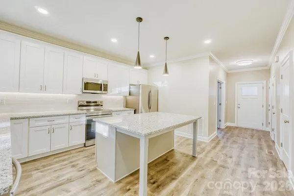 a kitchen with stainless steel appliances a stove a sink cabinets and wooden floor