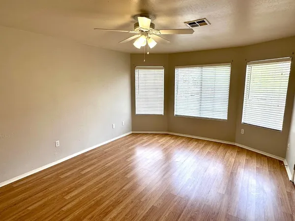 a view of an empty room with a window and wooden floor