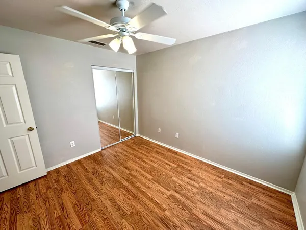 wooden floor in an empty room with a chandelier fan
