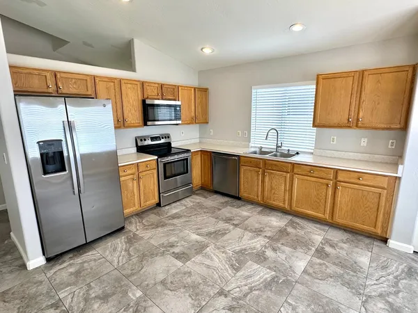 a kitchen with stainless steel appliances granite countertop a sink and a refrigerator