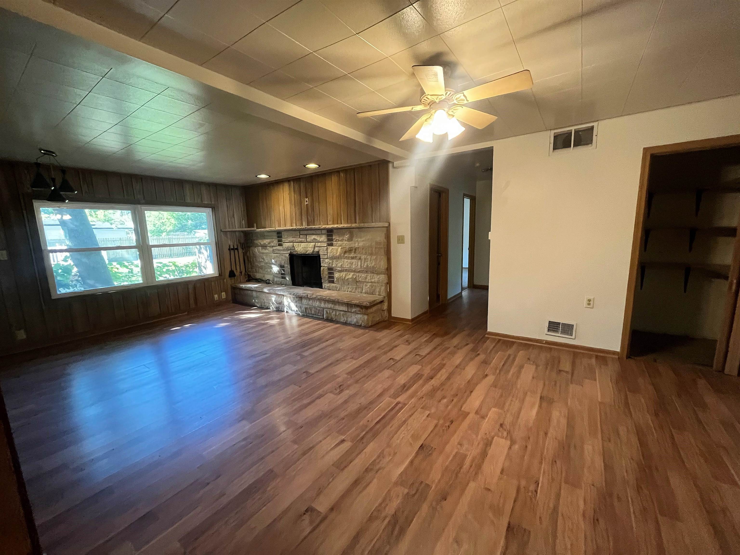 4026 Pinecrest Road Rockford, IL 61107 - Photo 9 of 27 an empty room with wooden floor fireplace and windows