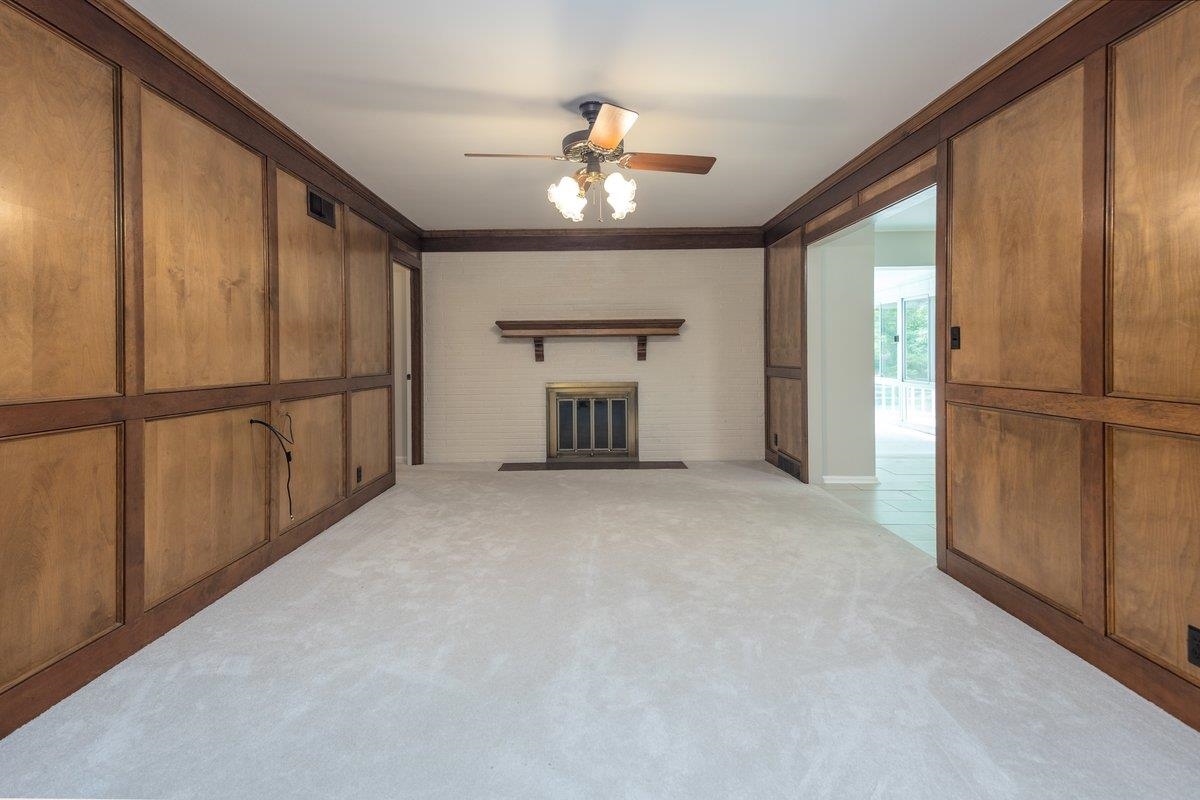 670 Peterson Lake Road Collierville, TN 38017 - Photo 15 of 37 Spacious room featuring light-colored carpeting, a fireplace with a brass-toned insert and wood mantel, and a ceiling fan with integrated lighting