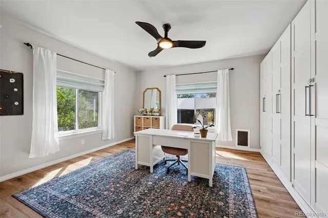 a work room with wooden floor a rug and a window