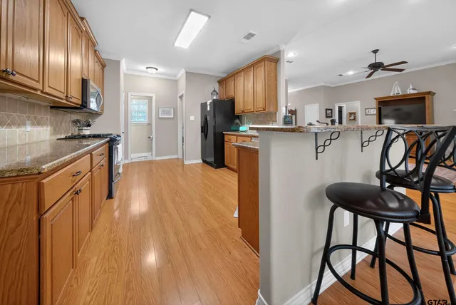 a kitchen with stainless steel appliances granite countertop a refrigerator a stove top oven a sink dishwasher and wooden cabinets